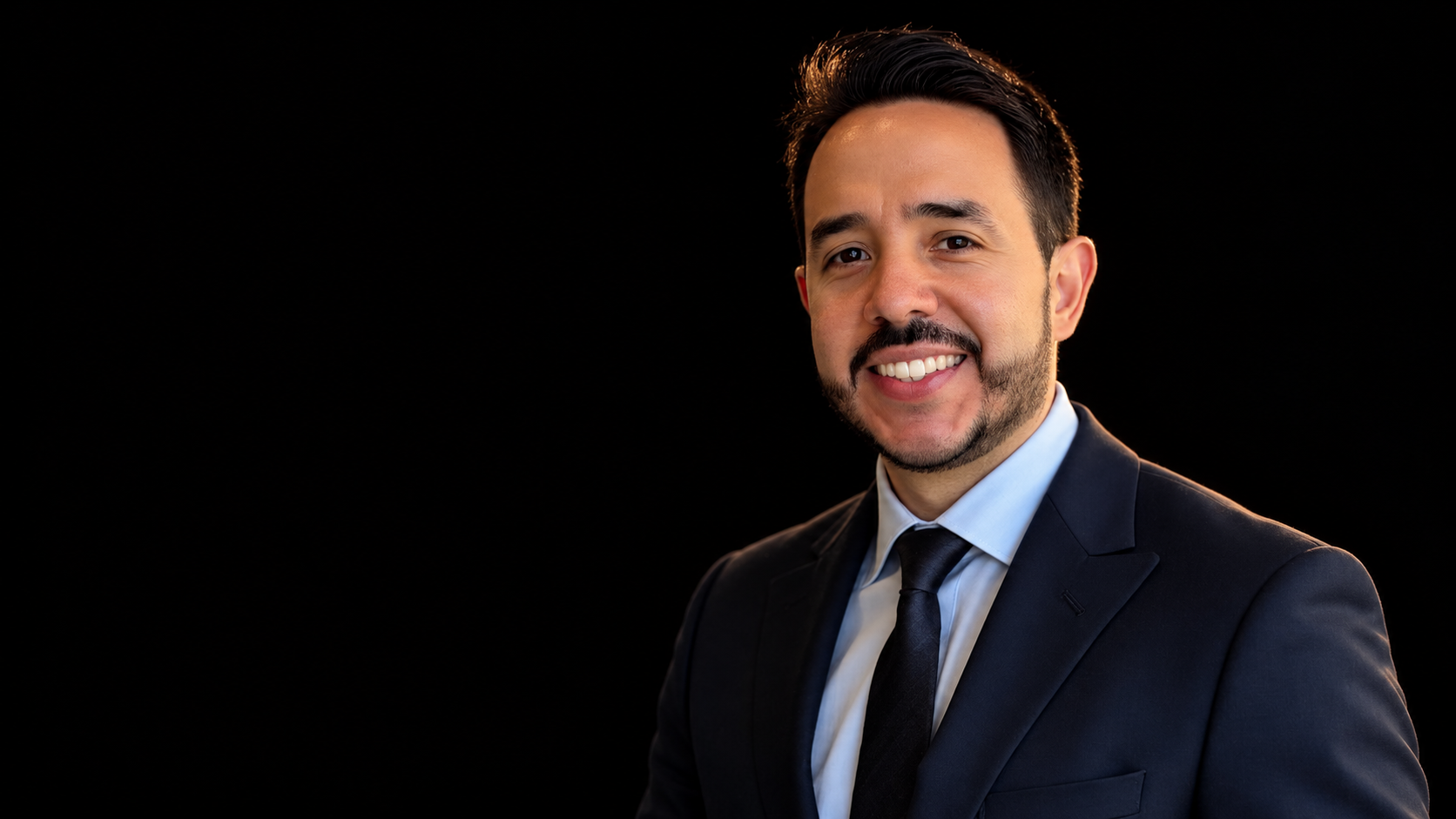 Smiling portrait in a dark suit, adapted against a black background